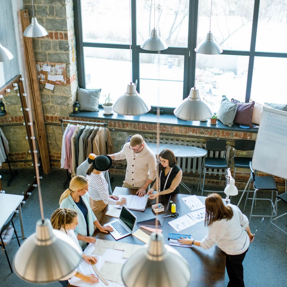 Cross-functional team reviewing plans and financial documents around a shared workspace